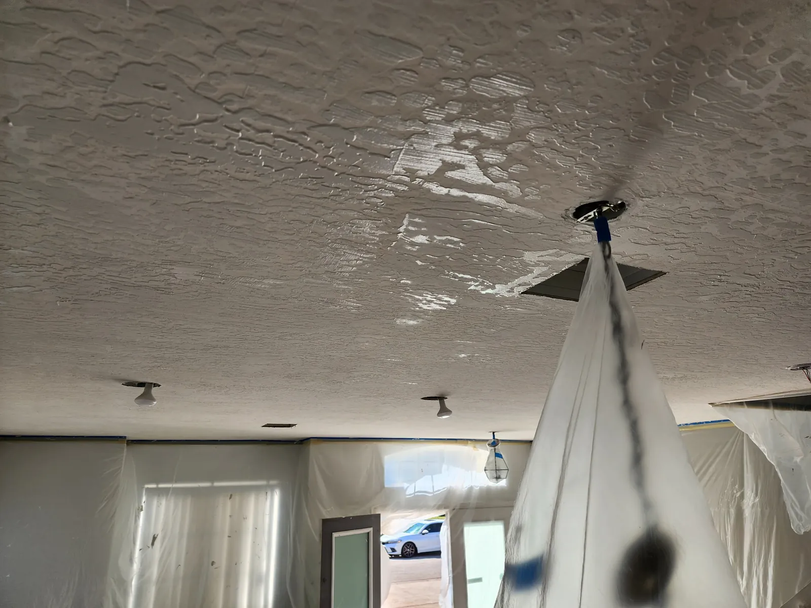 Fresh knockdown texture on a ceiling in low window light, showing the flattened pattern